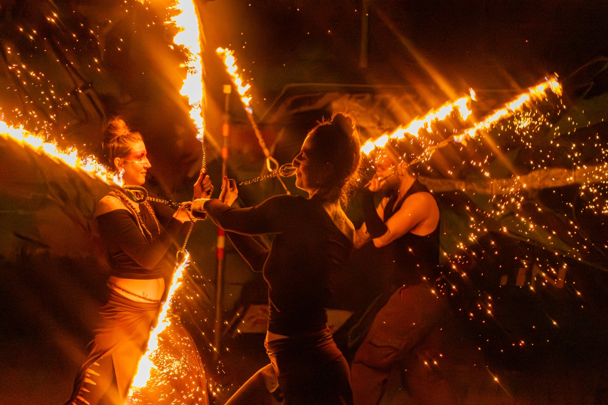 Feuerkünstler:innen mit Funkenstäben, sprühende Funken im Nachtdunkel