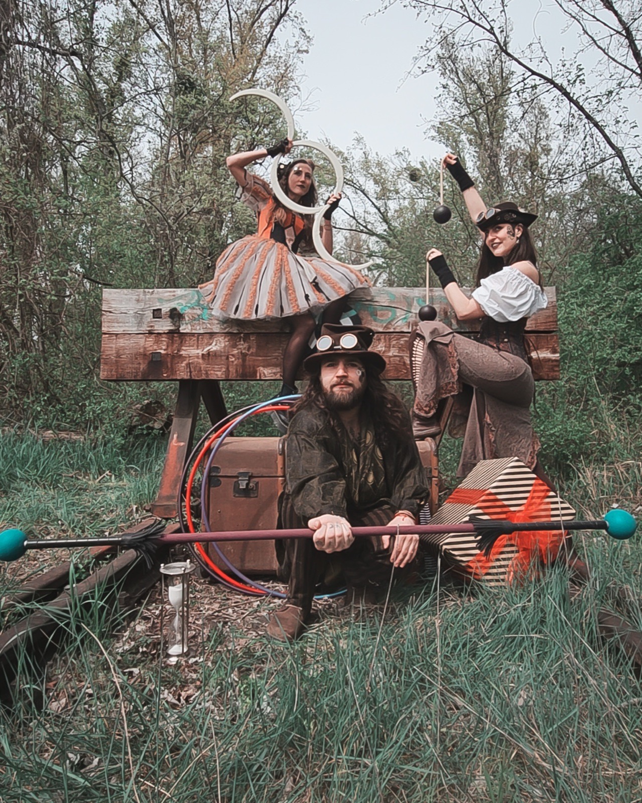 Steampunk-Trio mit Jonglierrequisiten, Reifen und Stab im Wald